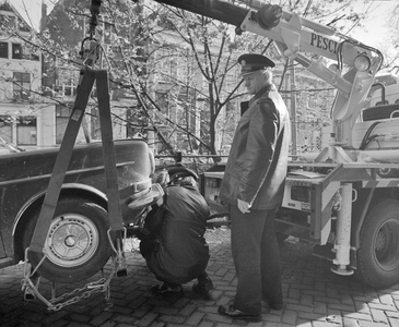 882175 Afbeelding van het wegtakelen van een personenauto door de verkeerspolitie, op de westzijde van de Nieuwegracht ...